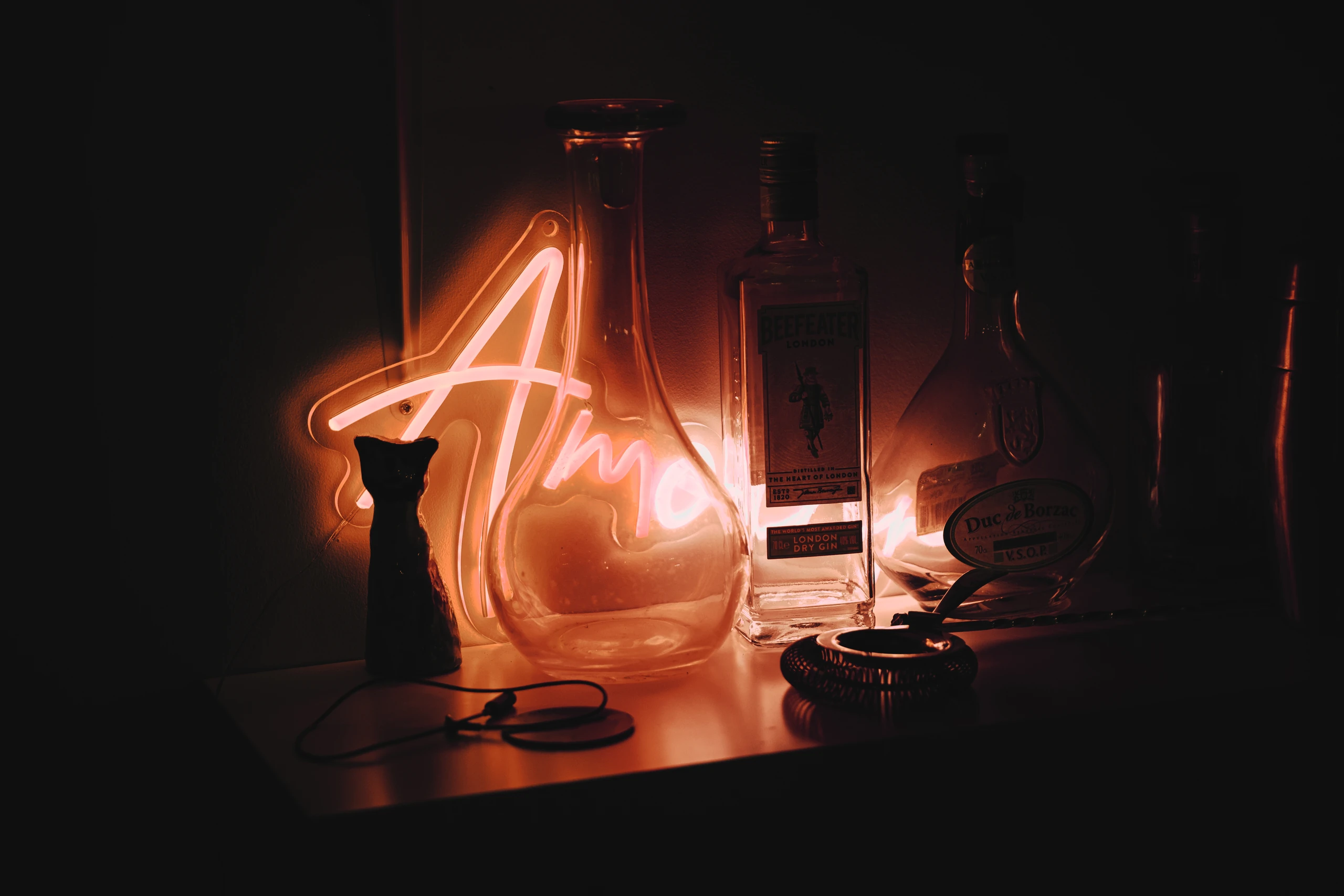 Orange neon light glowing among glass bottles in a dark interior