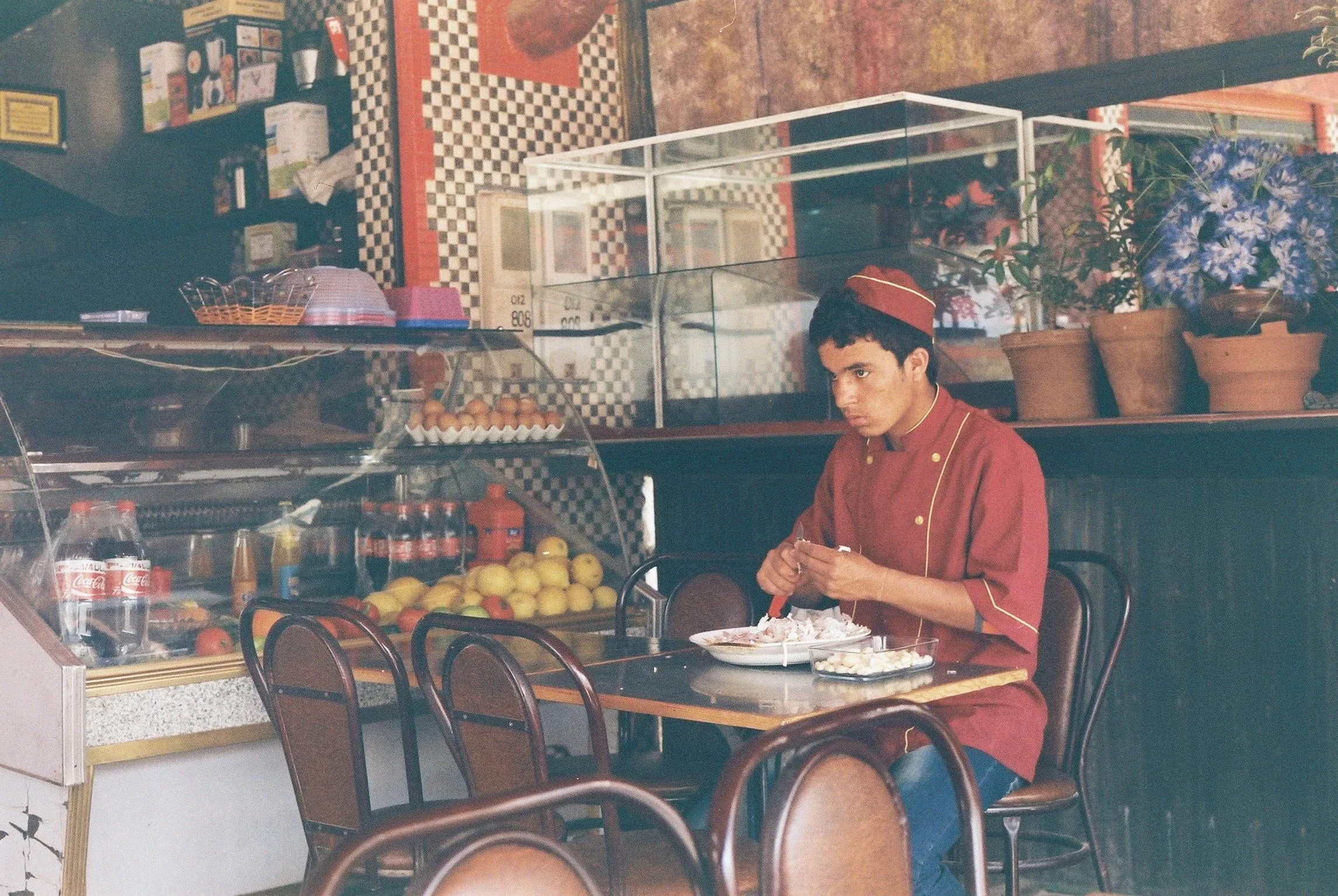 Young restaurant worker eating at a table beside a food counter