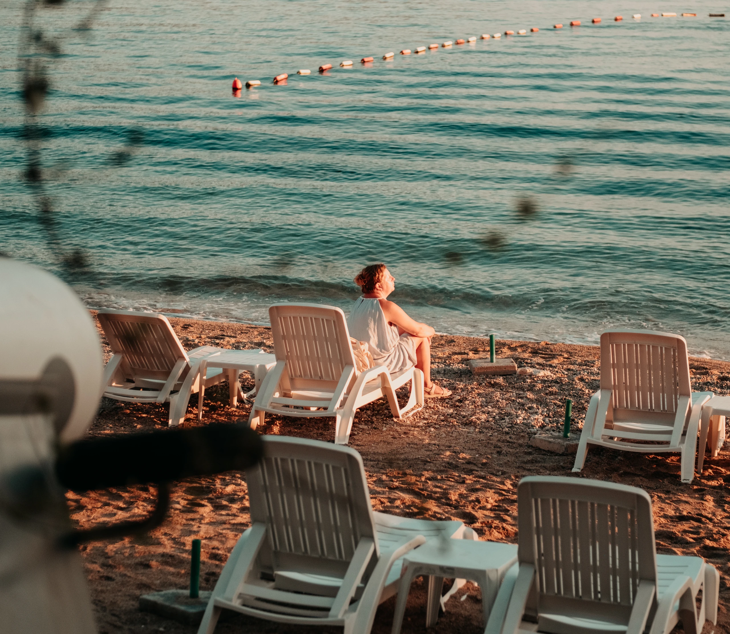 Person resting on a white sun lounger at the water’s edge