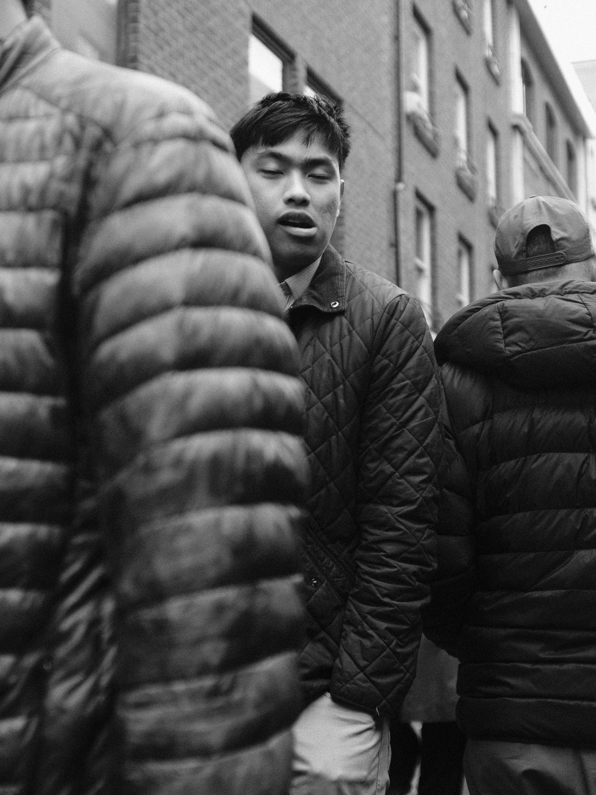 Black-and-white portrait of a young man among people in padded jackets